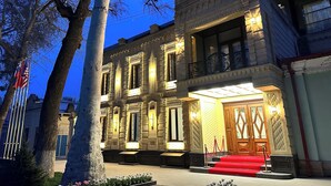 Un edificio histórico con un reloj, ventanas amplias y una entrada con alfombra roja.
