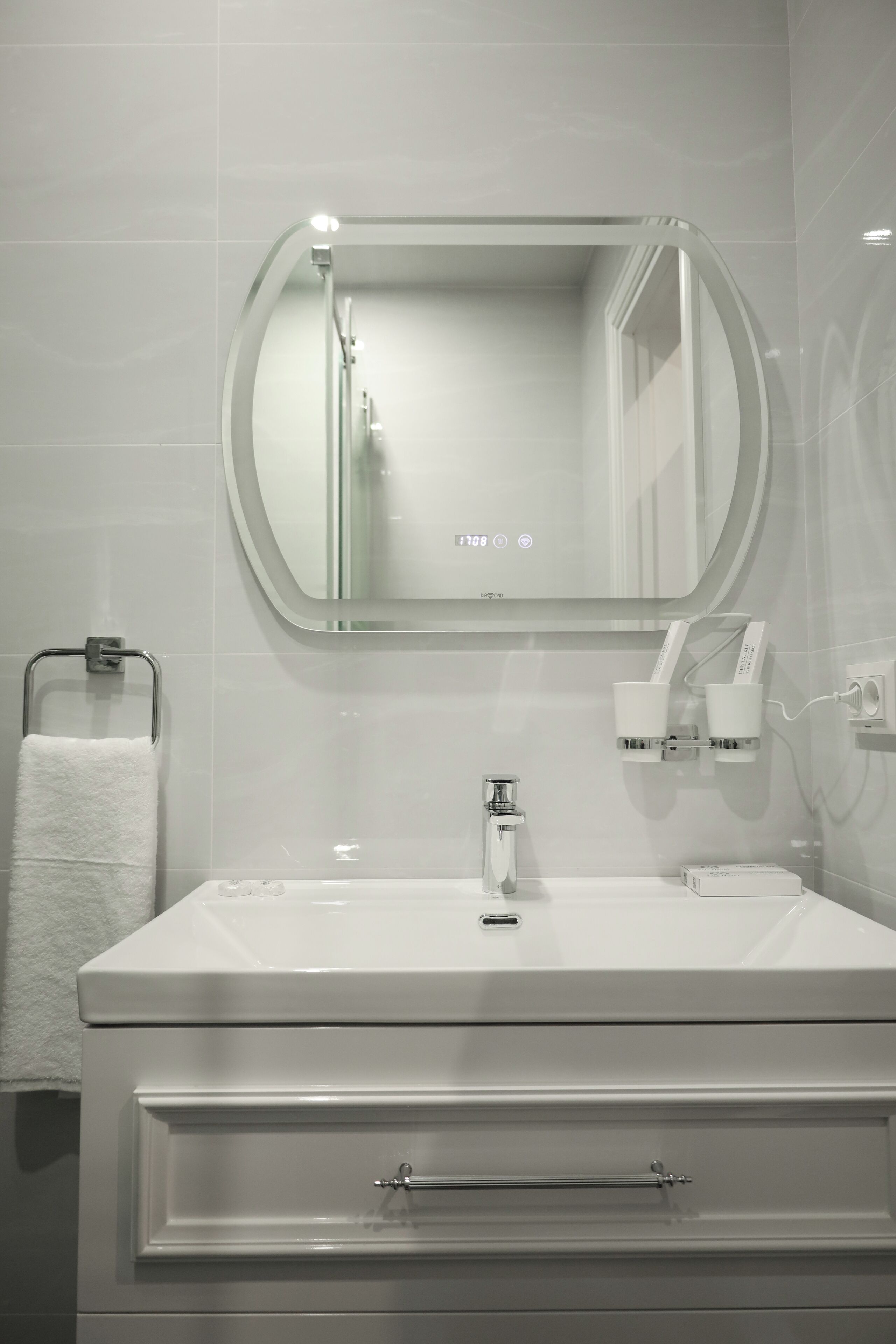 A modern bathroom with a white vanity, a round mirror, a towel rack, and a handheld showerhead.