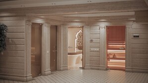 Un pasillo lujoso con columnas ornamentales, suelo con diseño y una zona de recepción con una pared decorativa.