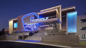 A modern building with a large illuminated sign reading "TOPGOLF".