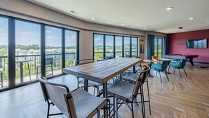 A spacious room with a large wooden table and chairs, a pool table, and a TV mounted on the wall.