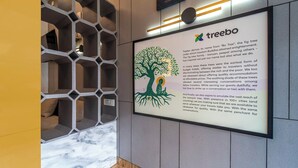 A framed informational sign about Treebo, a hotel chain, with a tree illustration and text. - Treebo MR Motel, 10 Mins To Airport (Iritty)