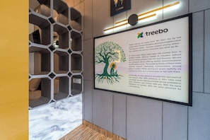 A framed informational sign about Treebo, a hotel chain, with a tree illustration and text. - Treebo MR Motel, 10 Mins To Airport (Iritty)