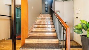 A staircase with wooden steps and a metal railing, leading to a room with a door and a sign indicating no smoking. - Treebo MR Motel, 10 Mins To Airport (Iritty)