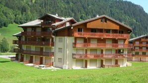 Un hotel de varios pisos con balcones y montañas al fondo.