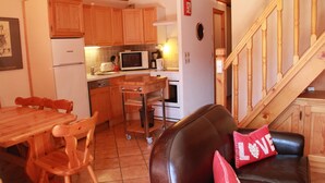 A cozy kitchen with wooden cabinets, a dining table with chairs, a microwave, and a stove. - Sorbiers Ss11 View & Quiet 6 Pers (Chatel)