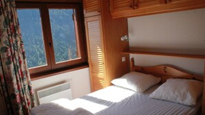 A bedroom with a bed, a window with curtains, and a view of a forest. - Sorbiers Ss11 View & Quiet 6 Pers (Chatel)