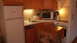 A compact kitchen with wooden cabinets, a built-in microwave, a sink, and a stove. - Sorbiers Ss11 View & Quiet 6 Pers (Chatel)