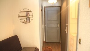 Un couloir avec un canapé marron, une porte et un élément de décoration fixé au mur.