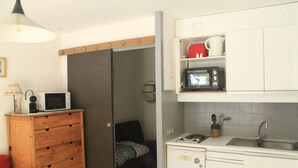 Une cuisine de taille réduite, équipée d’un four à micro-ondes, d’un évier et d’un petit placard.