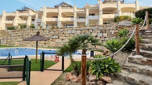 Un hotel con varios balcones, piscina y una pared de piedra.