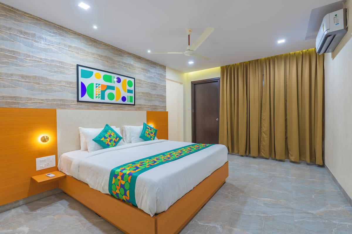 A modern hotel room with a large bed, a ceiling fan, an air conditioning unit, and a wall-mounted artwork.