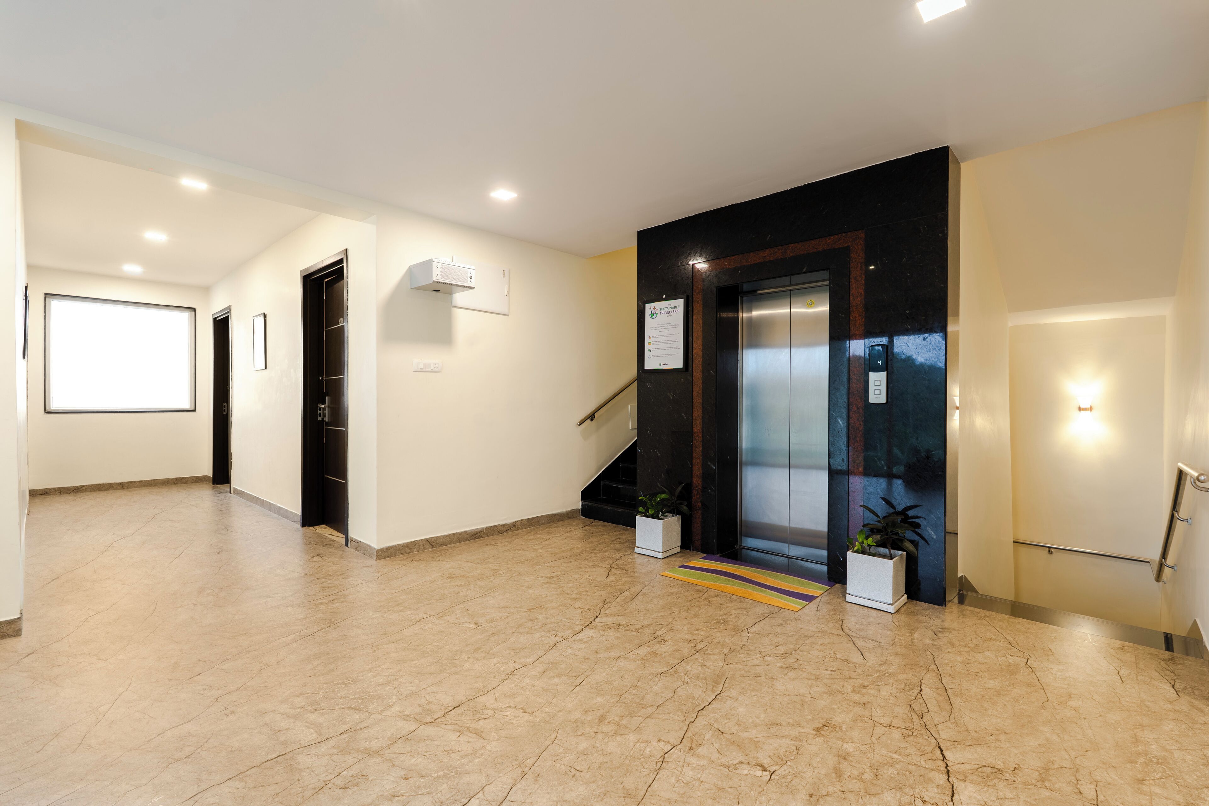A spacious lobby with a marble floor, a staircase, and a reception area.