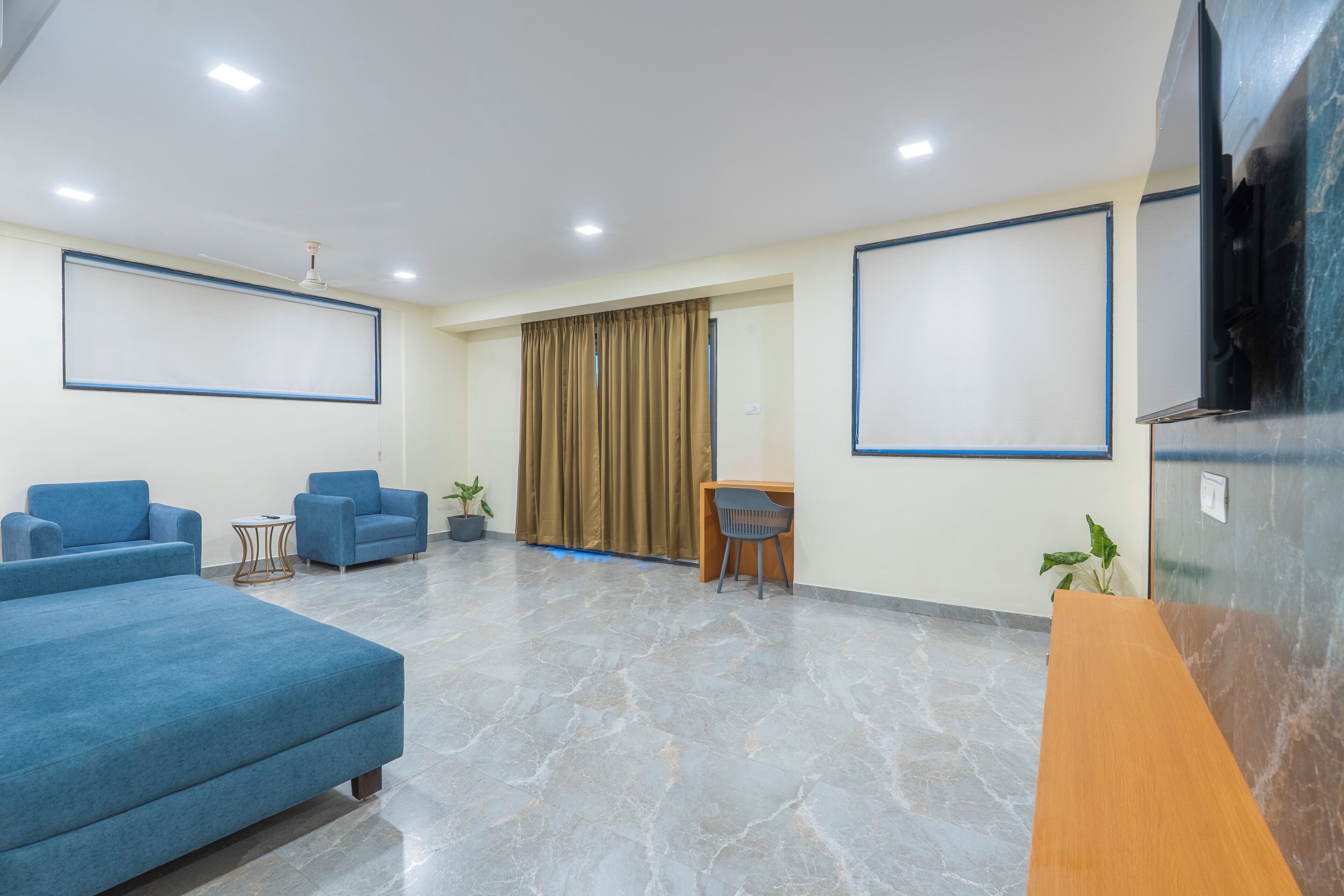 A modern waiting area with blue sofas, a wooden table, and a TV screen.