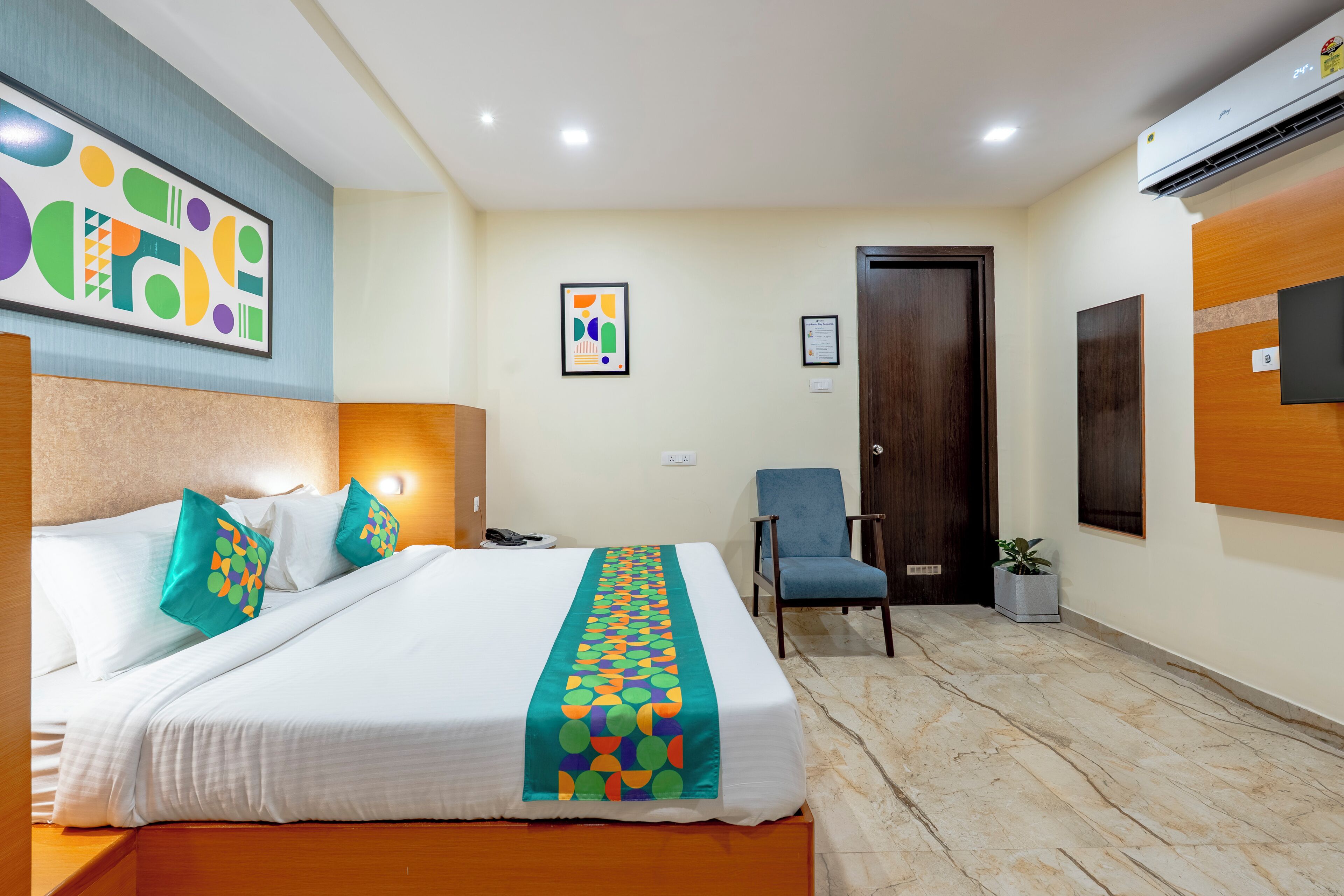 Une chambre d’hôtel avec un lit, une chaise, un bureau et une plante en pot.