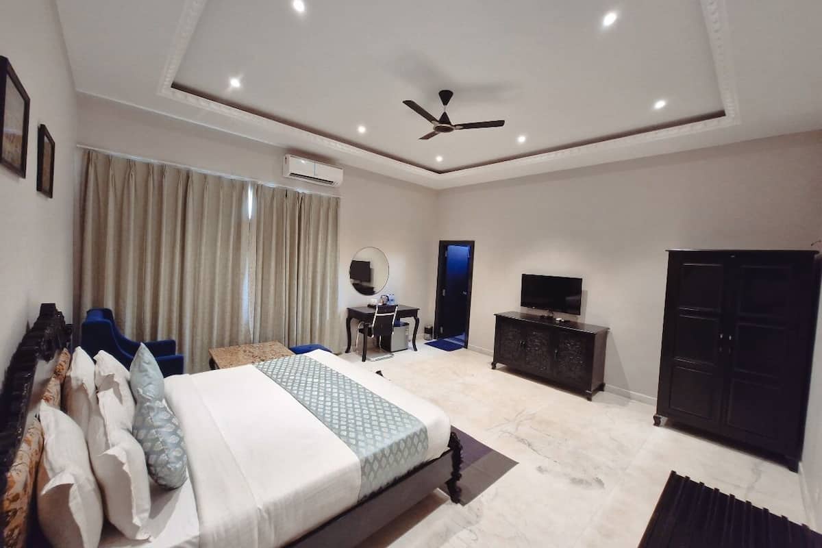 A modern hotel room with a large bed, a desk, a television, and a wardrobe.