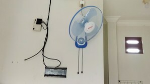 A wall-mounted fan with a power strip and a small vent. - Homestay Susanto (Pati)