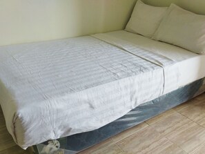 A single bed with a white mattress and a blue mattress cover. - Homestay Susanto (Pati)