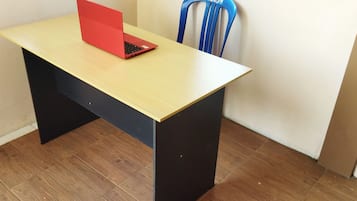 A small room with a wooden desk, a red laptop, and a blue chair.
