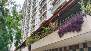 A multi-story building with balconies adorned with flowering plants and a checkered wall pattern. - Amerta Room Apartemen Mutiara by Cocotel (Bekasi)