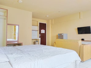Una habitación de hotel con una cama, un escritorio, un televisor y un refrigerador.