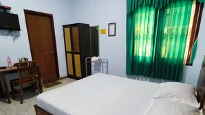 Quarto com cama, escrivaninha, cadeira, guarda-roupa e janela com cortinas verdes.