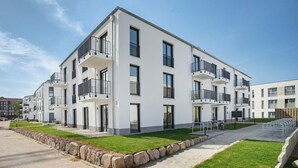 A modern multi-story residential building with balconies, a paved walkway, and a grassy area. - Top Loft Apartment with Private Terrace, Shared Garden, and Wi-Fi (Greifswald)