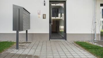 Entrada de un edificio con un buzón, una puerta con la etiqueta 'TH 4' y un pequeño espacio exterior con césped y un sendero.