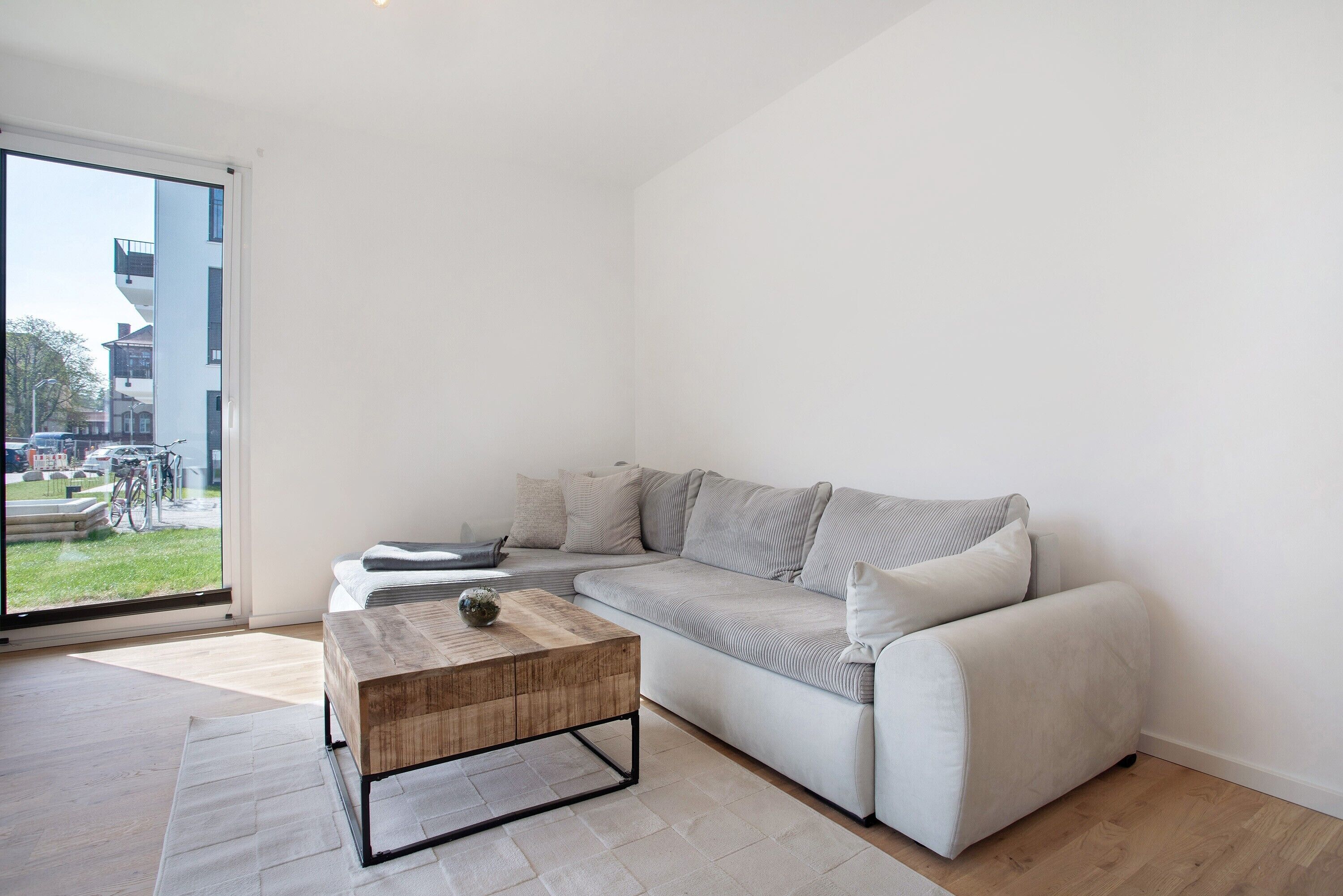 A modern living room with a sofa, coffee table, and a view through a glass door.