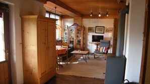 Een houten interieur met een betegelde vloer, een eethoek, een bank, een televisie en een open haard.