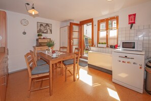 A kitchen with a wooden table, chairs, a microwave, and a refrigerator. - Holiday Apartment 'Im Strumpfweberhaus' with Private Terrace and Wi-Fi (Schiltach)