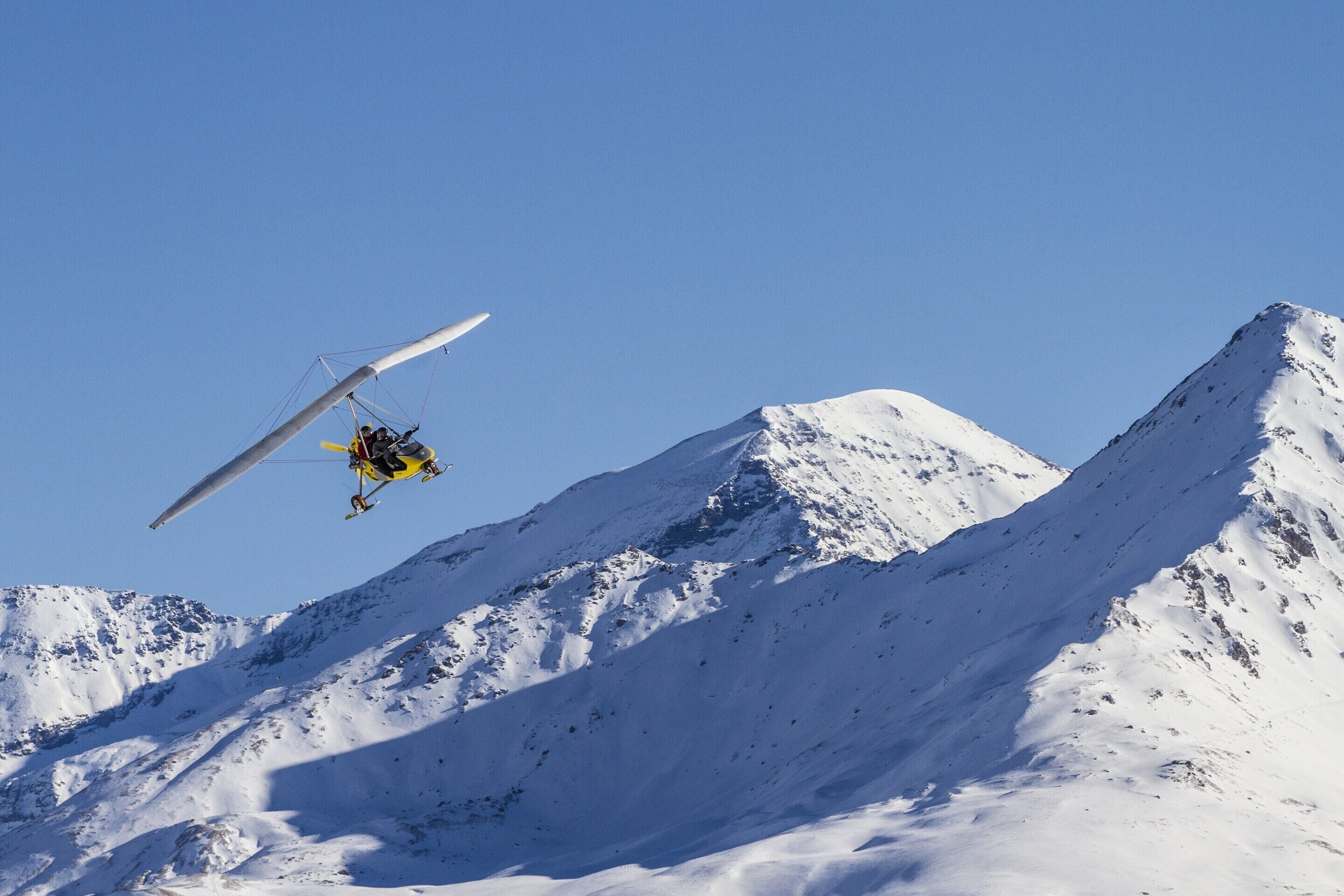 Lunta peittävä vuori, ja sen yllä lentävä helikopteri.