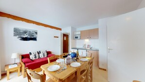 A compact living space with a dining area, kitchenette, and a red sofa with patterned cushions. - Apartment for 6 People in Val Cenis (Val-Cenis)
