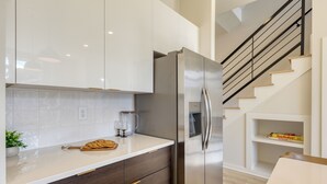 A modern kitchen with a stainless steel refrigerator, wooden cabinets, and a white countertop. - Newly Built 4BDR Townhome w/ Balcony, Minutes to Broadway | Lischey by AvantStay (Nashville)