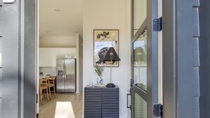 A modern kitchen with a refrigerator, wooden chairs, and a dining table. - Newly Built 4BDR Townhome w/ Balcony, Minutes to Broadway | Lischey by AvantStay (Nashville)