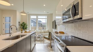 A modern kitchen with a large island, stainless steel appliances, and a view to the outside. - Newly Built 4BDR Townhome w/ Balcony, Minutes to Broadway | Lischey by AvantStay (Nashville)