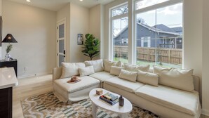 A living room with a sectional sofa, a coffee table, and a view of the backyard. - Newly Built 4BDR Townhome w/ Balcony, Minutes to Broadway | Lischey by AvantStay (Nashville)