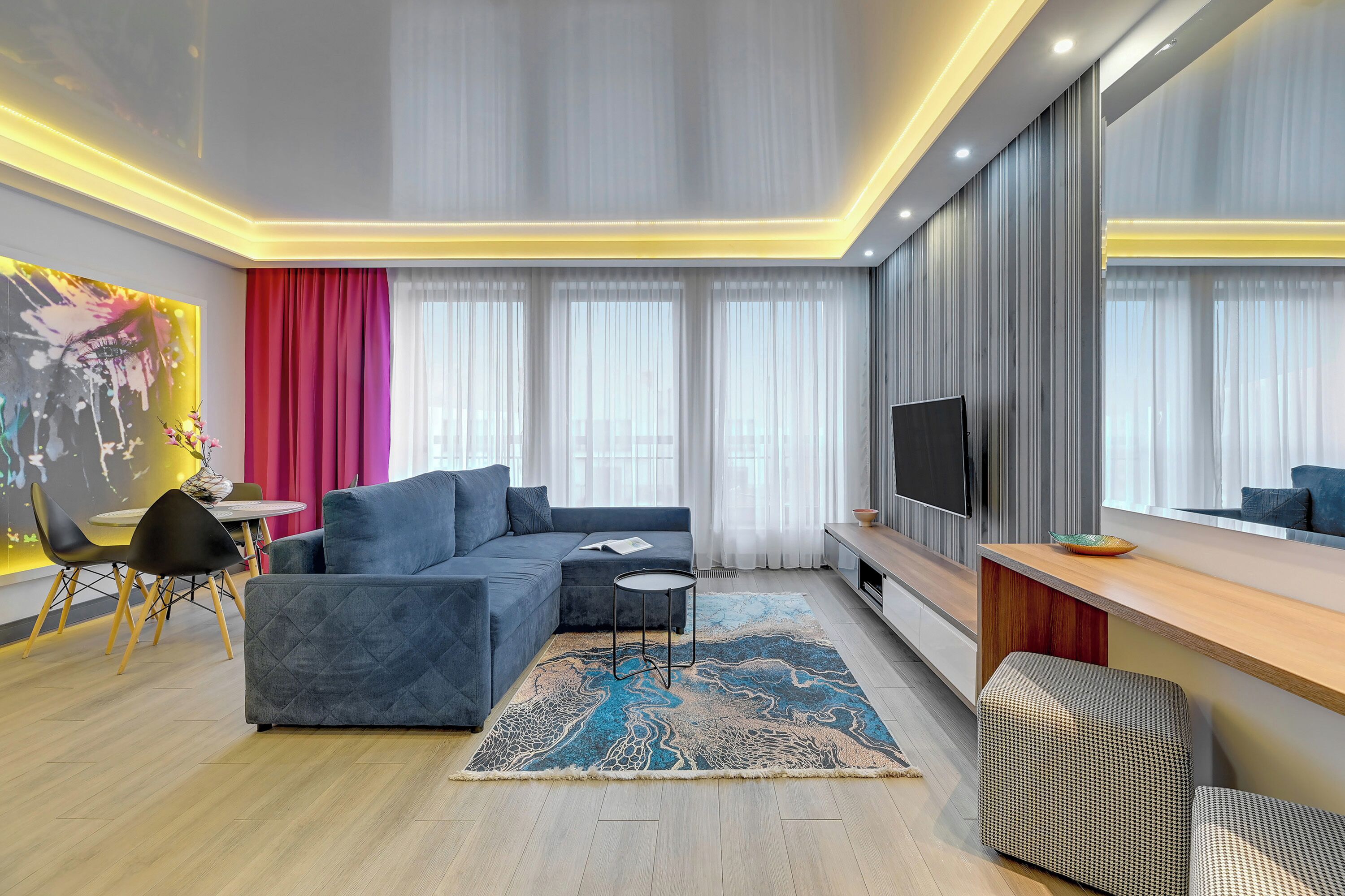 Ein modernes Wohnzimmer mit einem Ecksofa, einem kleinen runden Tisch und einem Flachbildfernseher.