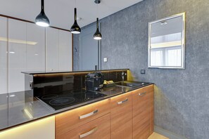 A modern kitchen with a black countertop, wooden cabinets, and pendant lighting. - Riverside Szafarnia Street by Downtown Apartments (Gdansk)