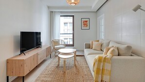 A modern living room with a TV, sofa, and a dining table. - Riverside Szafarnia Street by Downtown Apartments (Gdansk)