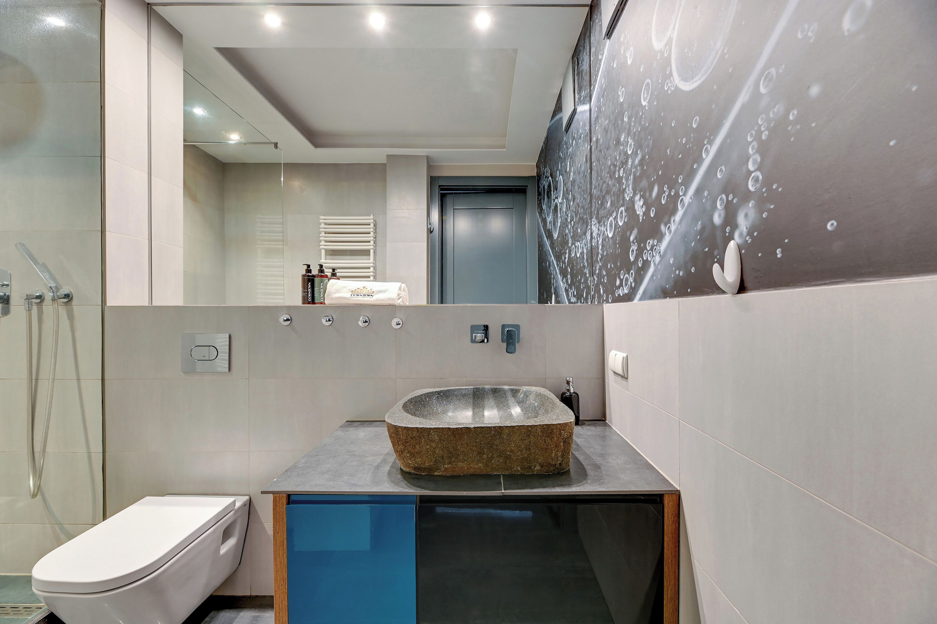 Een moderne badkamer met een wastafel van natuursteen, toilet en een douchecabine met glazen wanden.