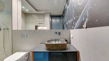 Een moderne badkamer met een wastafel van natuursteen, toilet en een douchecabine met glazen wanden.