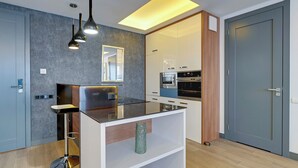 A modern kitchen with a bar stool, built-in oven, and a large window. - Riverside Szafarnia Street by Downtown Apartments (Gdansk)