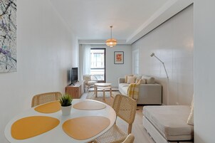 A modern living room with a sofa, coffee table, and dining area.