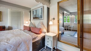 A bedroom with a bed, bedside table, lamp, and a large mirror. - Vacation home 'Poppenstuuv', idyllic baroque fairytale garden, sauna, parking, Wi-Fi (Stadum)