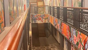 A corridor with a checkered floor, wooden railings, and walls adorned with floral patterns. - Alltrue Hotel Palangkaraya (Palangkaraya)