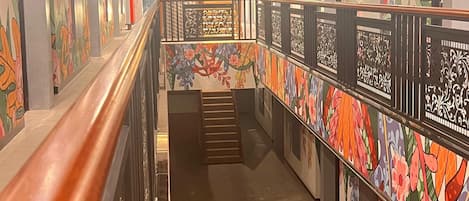 A corridor with a checkered floor, wooden railings, and walls adorned with floral patterns.