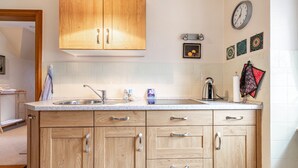 A kitchen with wooden cabinets, a sink, and a clock on the wall.