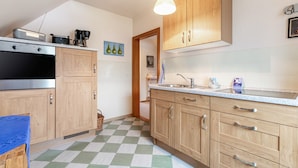 A kitchen with wooden cabinets, a stainless steel oven, a checkered floor, and a hanging light fixture.