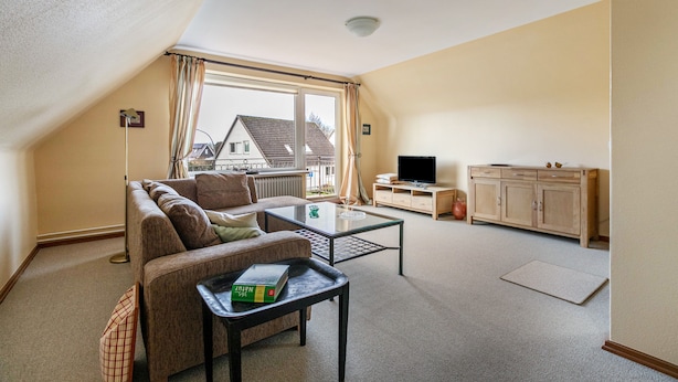 A cozy living room with a sofa, coffee table, TV, and a cabinet.